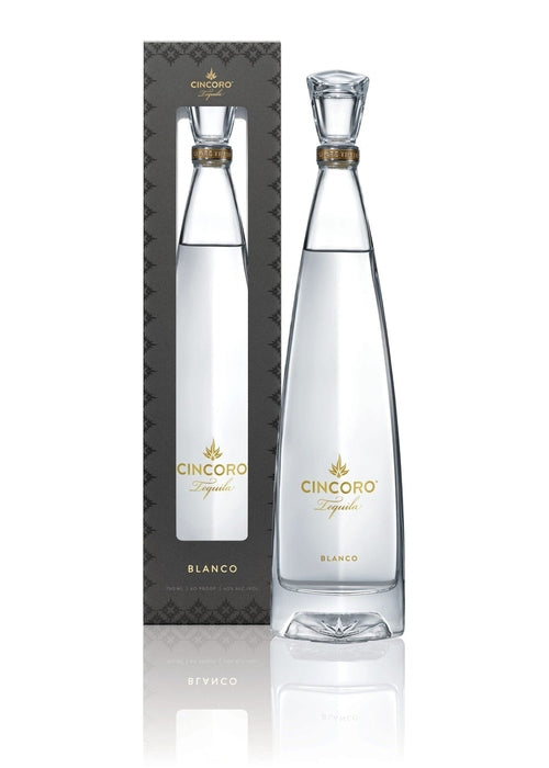 Cincoro Blanco 700ml tequila bottle with gold label and stopper beside dark gray packaging
